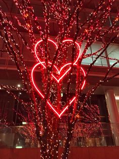 a lighted heart tree in front of a building with lights on the branches and around it