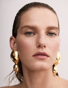 a woman with blue eyes wearing gold earrings