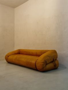 a couch sitting in the middle of a room with white walls and concrete flooring