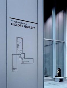 a person sitting on a bench in front of a building with a sign that says history gallery