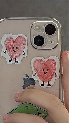 someone is holding up their phone case with stickers on it and there are two hearts in the shape of an apple