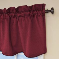 red curtains hanging on the side of a door with a curtain rod in front of it