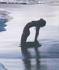 a woman kneeling down on top of a surfboard in the water at the beach