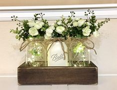 three mason jars with flowers in them on a shelf