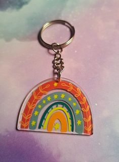 a keychain with a rainbow design on the front and back sides, hanging from a metal ring