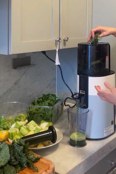 a person is using a juicer on a counter top with vegetables and other ingredients