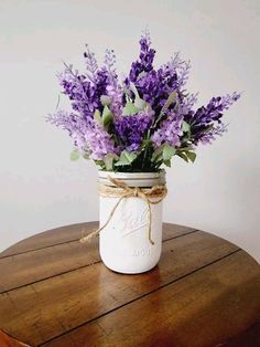 purple flowers in a mason jar tied with twine on top of a wooden table