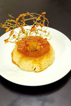 a white plate topped with food on top of a black table next to a fork and knife