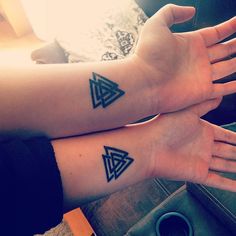 two people with matching tattoos on their arms, both holding each other's hands