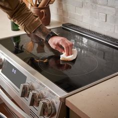 a man is cleaning his stove with a rag