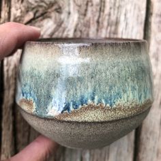 a hand holding a blue and brown bowl