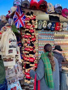 a woman standing in front of a store selling hats and scarves