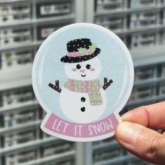 a person holding up a snow globe with a snowman on it