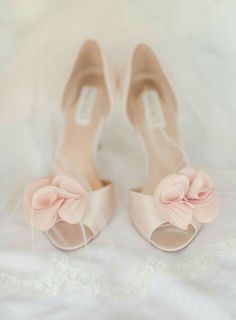 a pair of shoes with pink bows on the toes and heels are sitting on a white sheet