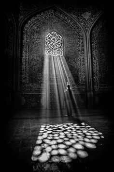 the light shines brightly from behind an open door in front of a wall with arabic writing