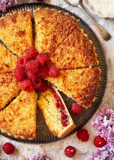 a cake with raspberries is cut into slices and served on a platter