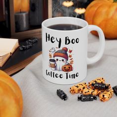 a cup of coffee with halloween cookies on the table next to it and some pumpkins