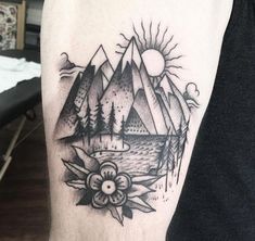 a black and white tattoo on the arm of a person with mountains in the background