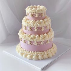 a three tiered cake with white icing and pink frosting