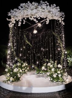 an outdoor wedding setup with white flowers and string lights