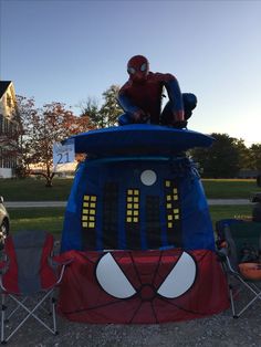 a man sitting on top of a blue and red inflatable spiderman tent