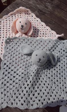 two crocheted blankets and a teddy bear on a wooden table next to each other