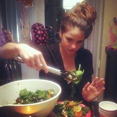 a woman is eating salad from a bowl