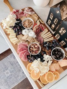 an assortment of cheeses, meats and fruit on a wooden platter