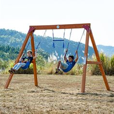 two children are playing on swings in the park