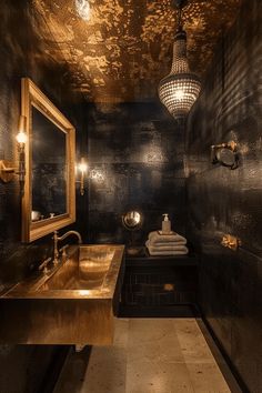 a bathroom with black walls, gold fixtures and a large mirror on the wall above the sink