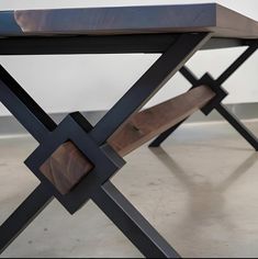 a wooden bench sitting on top of a cement floor next to a metal cross leg