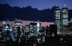 the city skyline is lit up at night, with skyscrapers in the foreground