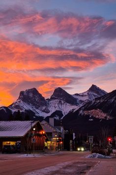 the mountains are covered in snow as the sun sets over town and ski lodges