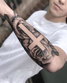 a man with a cross and roses tattoo on his arm