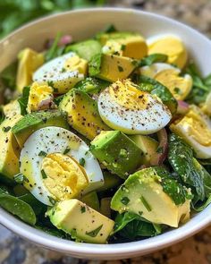 a white bowl filled with salad topped with hard boiled eggs and green leafy vegetables