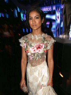 a woman in a white dress with flowers on her body and handbag at an event