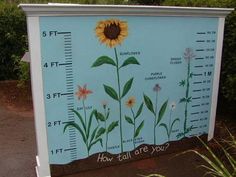 a blue and white sign with a sunflower on it's side in front of some bushes