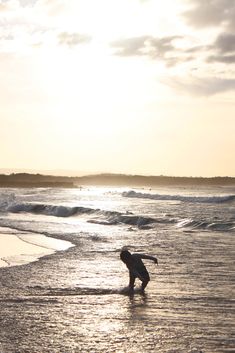 a person standing in the water on top of a beach