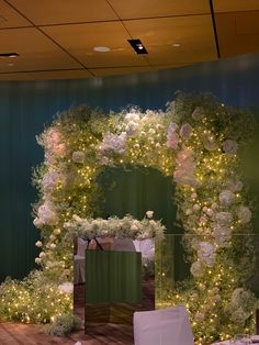 an archway decorated with white flowers and greenery is lit up at night for a wedding reception