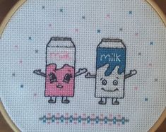 cross stitch pattern with two cartoon characters holding milk cans, one is pink and the other is blue