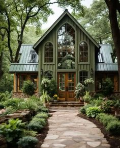 a house that is surrounded by trees and plants in the front yard with stone walkway leading up to it