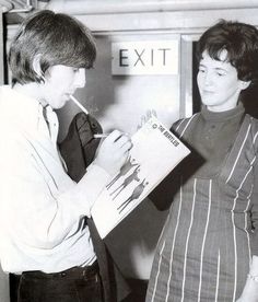 two women standing next to each other in front of an exit sign and one holding a clipboard