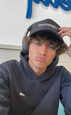 a young man wearing headphones and a hat