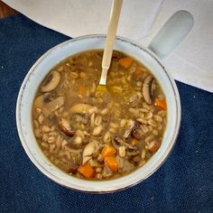 a bowl of soup with mushrooms and carrots in it on top of a blue cloth