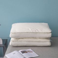 two pillows and an open magazine on a table next to a lamp with a blue wall in the background