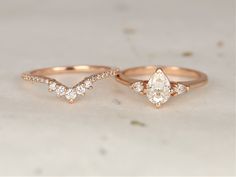 two wedding rings, one with a pear shaped diamond and the other with small diamonds