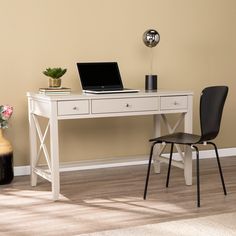 a white desk with a laptop on top of it next to a chair and vase