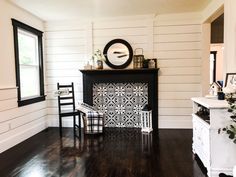 a black and white fireplace in the corner of a room with wood flooring on the side