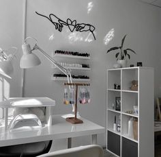 a white desk topped with a lamp next to a book shelf filled with lots of books