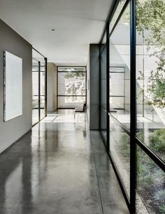 an empty hallway with glass walls and trees in the background